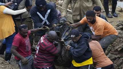 Residents and volunteers remove the body of a landslide victim