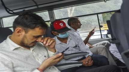 Mohammed Zubair center wearing cap sits in a police vehicle