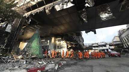 Cambodian and Thai rescue experts walk through a ruined building