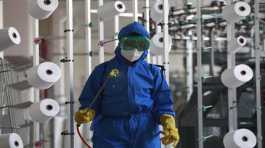 employee of Songyo Knitwear Factory in  disinfects the work floor in Pyongyang