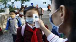 teacher takes the body temperature of a schoolgirl