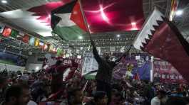 fans wave Qatari and Palestinian flags