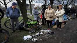 Local residents gather near a generator to charge their mobile devices