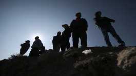 Migrants stand near the U.S. Mexico border