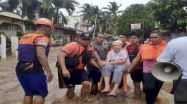 an elderly woman sits on a chair while being carried by coast guard