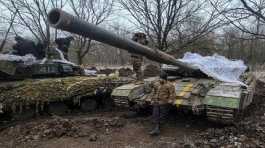 Ukrainian servicemen stand on their tanks