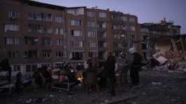 family gather around bonfires while rescue teams