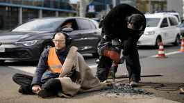 Police removes the pavement next to the hand of a climate activist during a protest