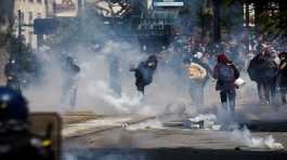 Demonstrators throw tear gas as they clash with police