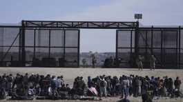 Migrants wait next to the U.S. border wall