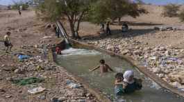 palestinians cool down in a spring