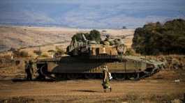 Israeli soldier walks past a tank